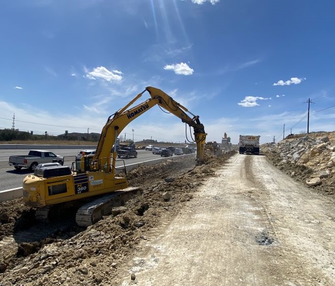 Oak Hill Parkway equipment operators crush rock and dirt alongside US 290 near Convict Hill Road. Crews are building walls in this area that will support the future westbound US 290 frontage road. April 2022
